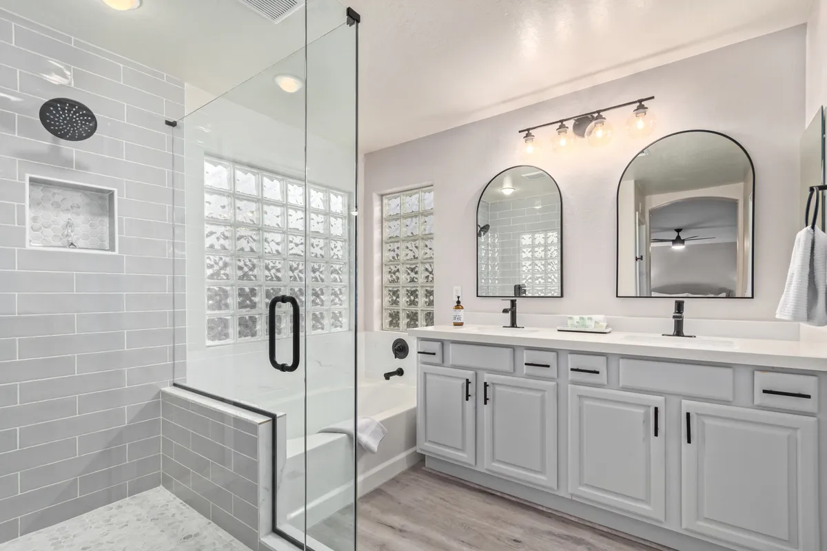 A modern bathroom with a glass shower enclosure, a freestanding bathtub, double vanities with mirrors, and sleek fixtures. The room is bright and feels like a private spa, perfect for relaxation and privacy.