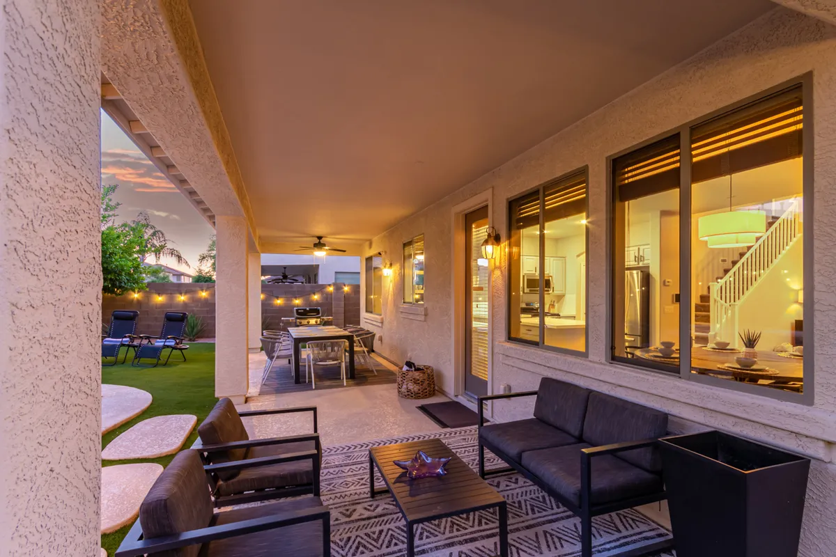 A covered outdoor seating area and dining table are arranged on the patio, complete with soft lighting and an inviting ambiance. The area is designed for al fresco dining, relaxing with friends, or evening conversations under the Arizona sky.