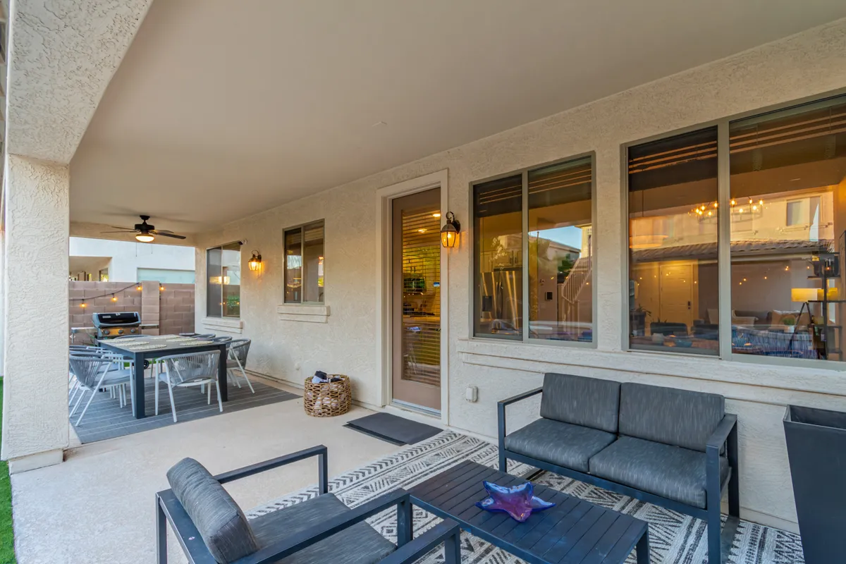 This exterior image features an outdoor seating area and dining table set on a patio, with windows offering a glimpse into the home's interior. The setup encourages alfresco dining, relaxation, and entertaining guests in a welcoming environment.