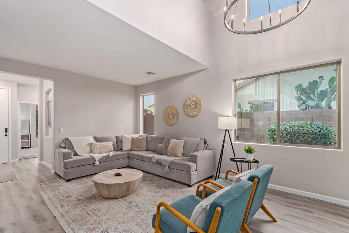A comfortable lounge area is arranged with a large sofa, a round coffee table, sizeable decorative wall hangings, and a generously sized window letting in sunlight. The setting is inviting for lounging, chatting, or hosting informal get-togethers, spotlighting the section’s focus on comfort and sociability.